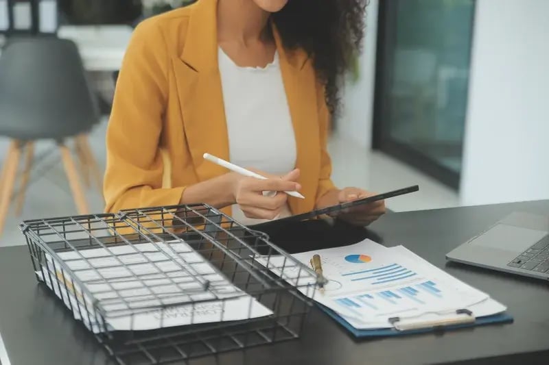 Mujer revisando gráficos financieros y documentos relacionados con un plan de cuenta en una oficina