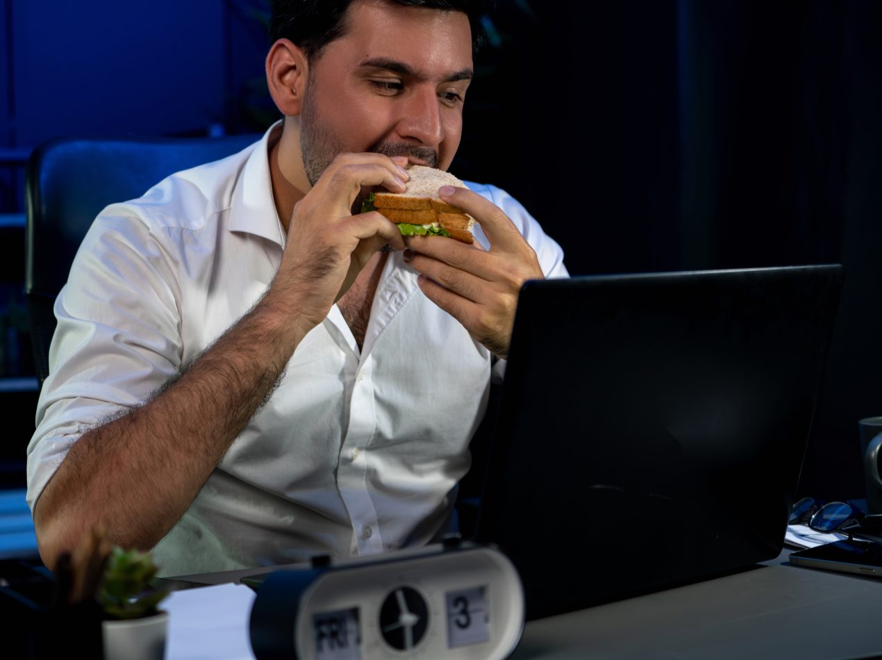 el hombre de negocios disfruta comiendo con un delicioso sandwich en el escritorio vendible